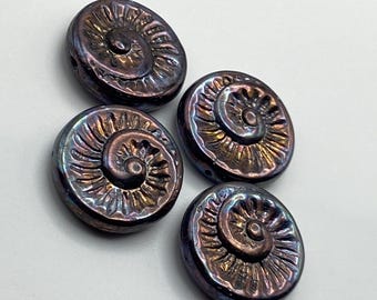 Four Czech spiral fossil coin beads in black nebula with bronze wash, showing ammonite spiral detail, on a plain background.