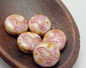 Five beige Czech glass bird coin beads with metallic pink detailing and gold speckles, displayed in a wooden dish.