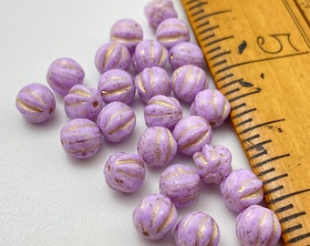 Czech glass fluted melon beads in lilac with gold wash, shown next to a wooden ruler for scale.