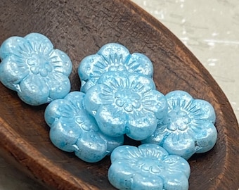 Six aquamarine Czech glass flower beads with detailed petals and centres, displayed in a wooden bowl.