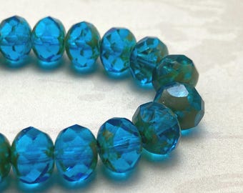Capri blue faceted rondelle beads with Picasso finish arranged in two loose rows on a white background.