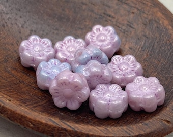 Twelve pale pink Czech glass flower beads in a wooden bowl on a white background.