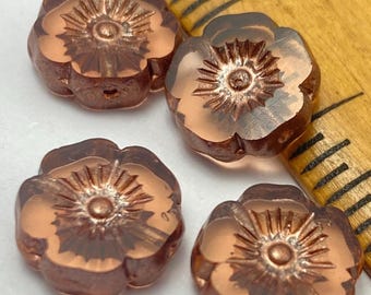 Four rosewood Czech table cut hibiscus flower beads with bronze finish on a wooden dish, showing the sunburst petal detail.
