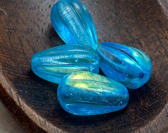 Four aqua blue fluted melon drops with iridescent finish rest in a dark wooden dish.