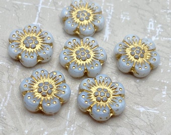 Six white alabaster anemone flower beads with gold wash detail arranged on a plain light background.