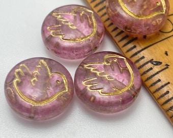 Four round Czech glass coin beads in clear pink with gold bird design, shown next to a ruler for scale.