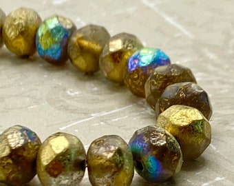 Czech glass rondelle beads in gold luster with AB finish iridescence arranged on a pale background, showing their faceted.