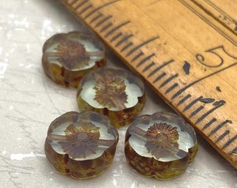 Four clear grey picasso Czech glass flower beads beside a ruler for scale on a light background.