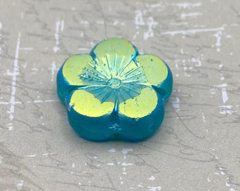 Single sea blue green Czech table cut hibiscus flower bead with yellow petals and AB finish on a plain background.
