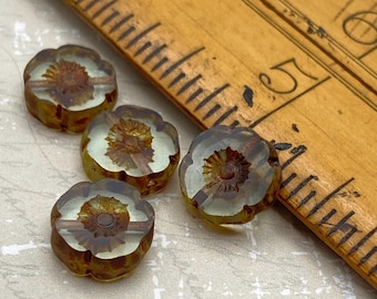 Four clear grey picasso Czech glass flower beads beside a ruler for scale on a light background.