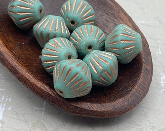 Eight matte turquoise Czech glass tribal bicone beads with copper wash stripe detail in a wooden dish.