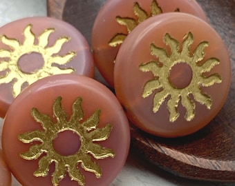 Five salmon pink Czech glass sun coin beads with gold wash details, displayed on a wooden dish.