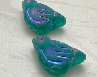 Two matte emerald green Czech bird beads with rainbow wash effect displayed on a plain background.