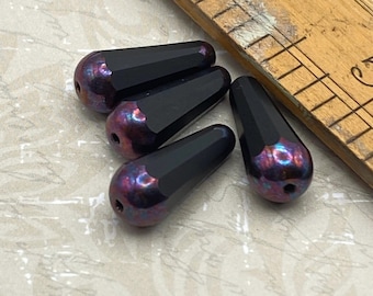Four Czech glass faceted drop beads in black with purple iridescent accents, shown with a ruler for scale.