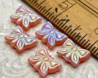 Five pink Czech glass butterfly beads with AB iridescent finish displayed next to a wooden ruler for scale.