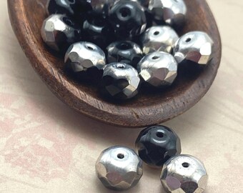 Black and silver faceted Czech glass rondelle beads in a wooden bowl, approximately fifteen beads visible