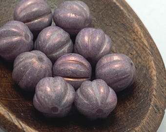 Ten plum purple lustre melon beads with rounded ridges displayed in a wooden bowl.