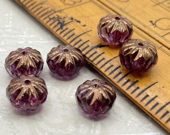 Five purple Czech glass cruller beads with bronze finish arranged next to a wooden ruler for scale.