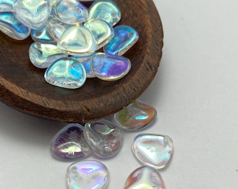 Czech glass rose petal beads in crystal AB with iridescent finish, scattered on a wooden bowl and plain background.