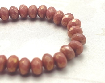 Approximately thirty orange brown Czech rondelle beads with gold lustre arranged in a loose arc on a pale cream background.