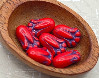 Six ladybug red Czech tulip bud flower beads with sapphire blue wash in a wooden bowl.