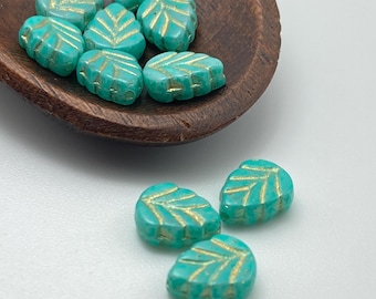 Czech glass leaf beads in mint green with gold detail, shown in a wooden bowl and scattered on a white surface.