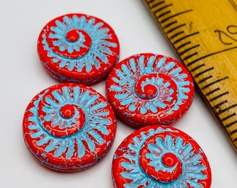 Four red Czech glass fossil coin beads with turquoise wash detail next to a yellow ruler for scale on a white background.