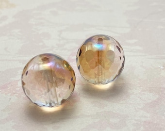 Two champagne gold Czech fire polished round beads, 18mm, faceted and iridescent on a pale background.