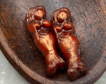 Two rustic red Picasso Czech glass mermaid beads with metallic highlights displayed on a dark wooden surface.