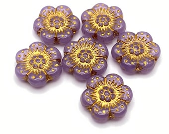 Six Czech glass anemone flower beads in lilac with gold detailing arranged on a plain background.