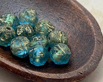 Ten sky blue Czech glass beads with gold etched finish in a dark wooden bowl on a plain background.