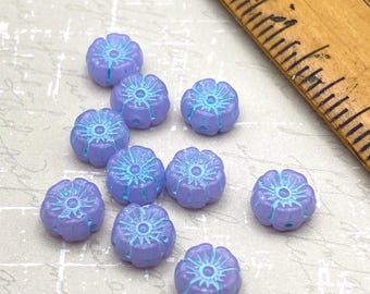 Ten Czech glass hibiscus flower beads in lilac with aqua blue wash, shown next to a wooden ruler for scale.