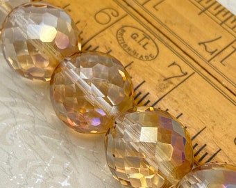 Champagne gold Czech faceted glass beads in warm amber tones, showing their multi-faceted surfaces and iridescent finish.
