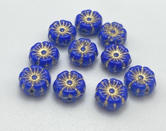 Ten opaque blue Czech glass hibiscus flower beads with gold wash detailing on a white background.