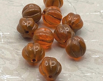 Ten burnt orange Czech glass melon beads with deep fluted grooves, displayed on a pale background.