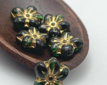 Five dark green Czech glass puffed daisy flower beads with gold wash detail, arranged on a wooden dish.