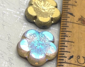 Two Czech glass hibiscus flower beads displayed next to a ruler: one solid gold, one blue AB with etched gold finish.