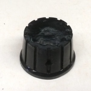May include: Black plastic knob with a ridged design. The knob has a small hole in the center.