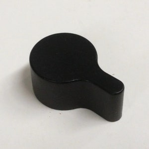 May include: Black plastic knob with a rounded top and a curved handle. The knob is designed for use with a variety of furniture and appliances.