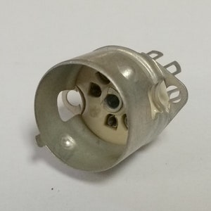 May include: A silver metal light bulb socket with a white ceramic base and five contact points.