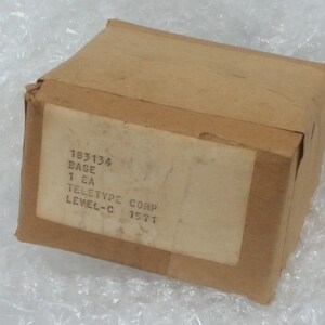 May include: A brown cardboard box with a white label that reads "183134 BASE 1 EA TELETYPE CORP LEVEL-C 15771".