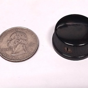 May include: A black plastic knob with a small hole in the center. The knob is about the size of a US quarter.