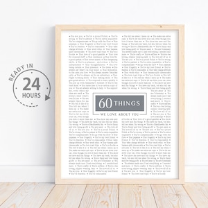 May include: A framed print with a gray background and white text listing 60 things we love about you. The text is in a handwritten font and includes a variety of positive attributes. The print is surrounded by a light brown frame.
