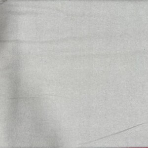 May include: A plain white fabric swatch. The fabric has a slightly textured surface.