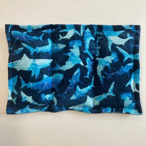May include: A blue and white fabric pouch with a geometric pattern of sharks. The pouch has a zipper closure and is perfect for storing small items.