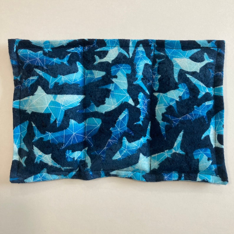 May include: A blue and white fabric pouch with a geometric pattern of sharks. The pouch has a zipper closure and is perfect for storing small items.