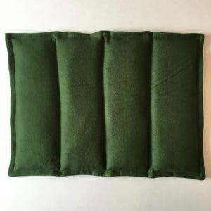 May include: A dark green rectangular heating pad with three sewn-in compartments. The pad is made of a soft, plush fabric.