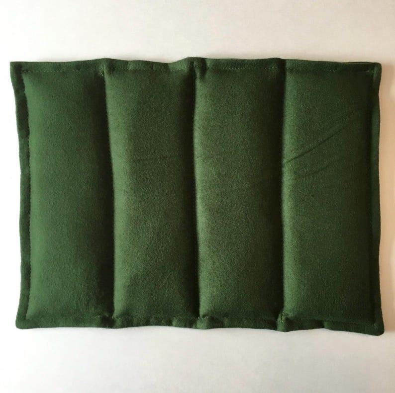 May include: A dark green rectangular heating pad with three sewn-in compartments. The pad is made of a soft, plush fabric.