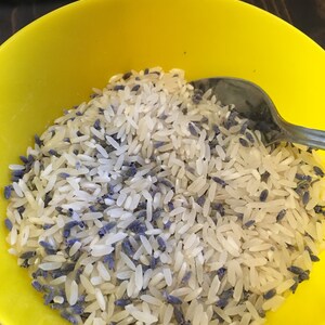 Puede incluir: Un bol amarillo lleno de arroz blanco y flores de lavanda secas.
