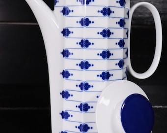 Pode incluir: Bule de café de cerâmica branca com um padrão geométrico azul e branco. A bule tem uma tampa com a parte superior azul.